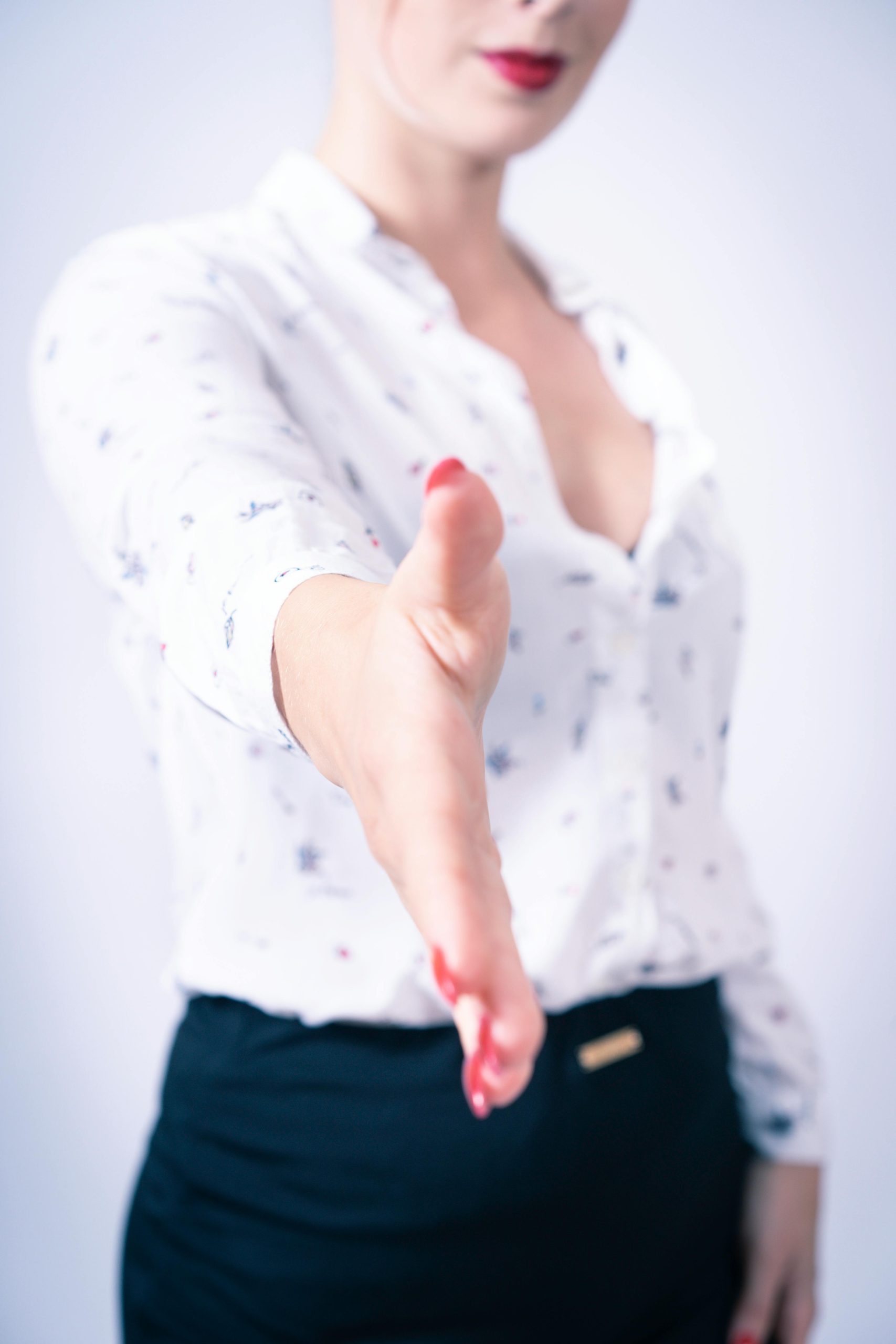 Close-up of a woman in a professional attire reaching out for a handshake symbolizing business opportunities.